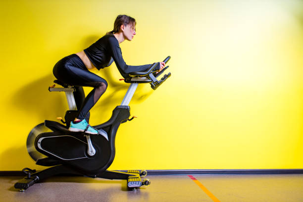 woman cycling on the machine trainer exercising in the gym stock photo