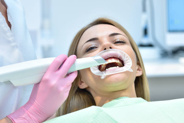 Woman dentist using dental intraoral scanner while examining patient teeth stock photo