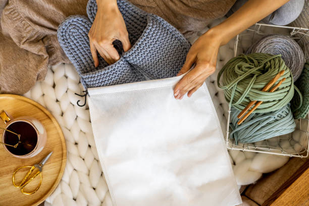 woman designer hands packing handmade knitting ribbon yarn slippers into branding pack sending order - breipakketten stockfoto's en -beelden