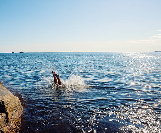 Woman diving, legs and splash, Vestfold Norway Woman diving, legs and splash, Vestfold Norway diving into water stock pictures, royalty-free photos & images
