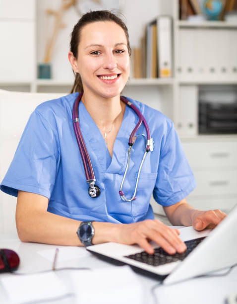 Woman doctor sitting at workplace with computer in office stock photo