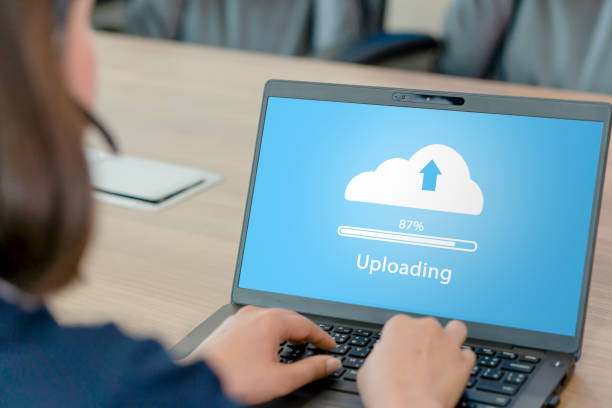 Woman doing cloud uploading on laptop in office. stock photo