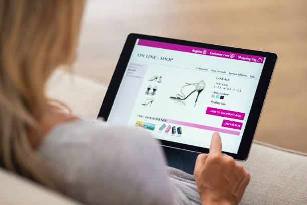 Woman doing online shopping Closeup of woman doing online shopping on digital tablet at home. Rear view of woman hand touching screen while selecting shoes on ecommerce portal. Lady use e-commerce webshop to buy shoes. online shopping stock pictures, royalty-free photos & images