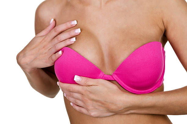 Woman doing self examination Woman wearing a pink bra examining herself for breast cancer bra stock pictures, royalty-free photos & images