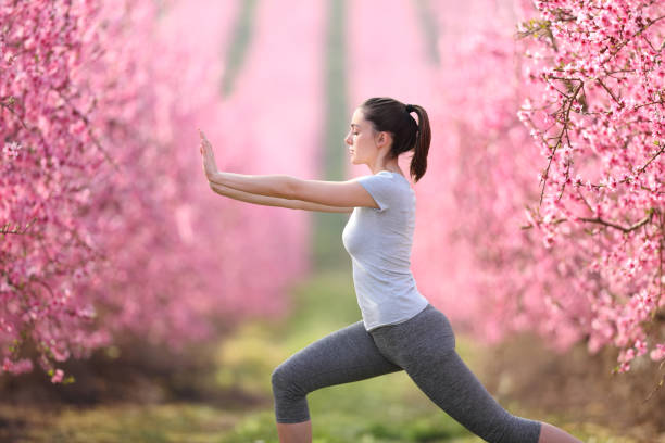 Woman doing tai chi exercise in a pink flowered field stock photo