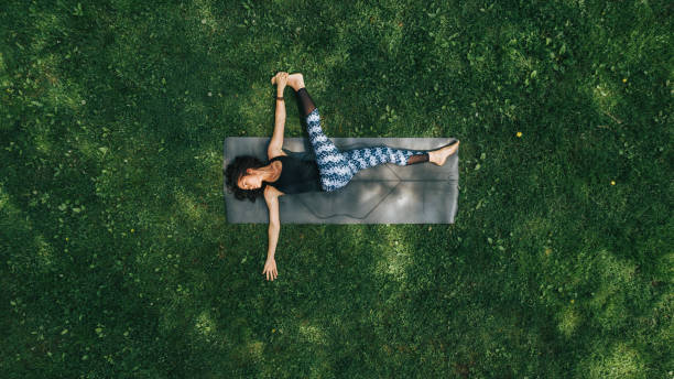 Woman doing Yoga in the Park Aerial View of Woman doing Yoga in the Park natural parkland stock pictures, royalty-free photos & images