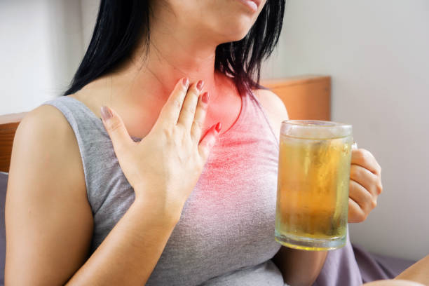 woman drinking beer having problem with GERD , acid reflux, and heartburn with gastritis stock photo