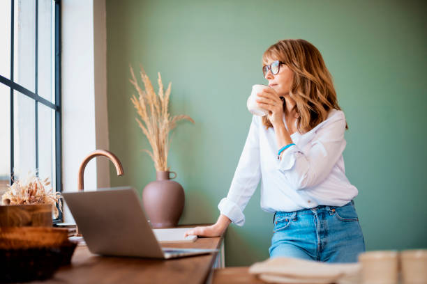 Woman drinking her coffee in the kitchen at the morning stock photo