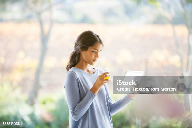 Woman drinking orange juice and using digital tablet