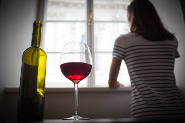 Woman drinking wine alone in the dark room stock photo