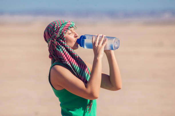 Woman drinks water in the desert of Egypt. Hot weather concept Woman drinks water in the desert of Egypt. Hot weather concept. hot egyptian women stock pictures, royalty-free photos & images