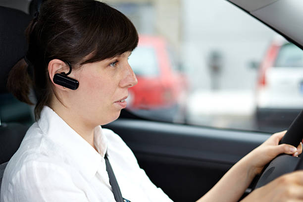 woman driving and talking phone in a car using headset stock photo