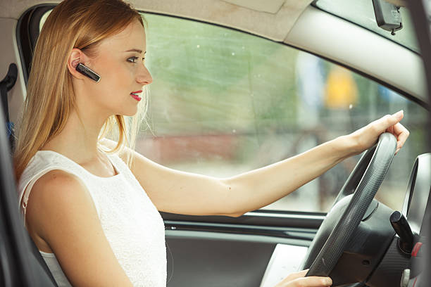 woman driving car with headset Transport and safety concept. Young blonde woman driving car using her mobile phone and headset, side view bluetooth stock pictures, royalty-free photos & images