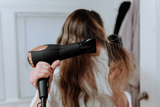 woman drying her hair with dryer stock photo