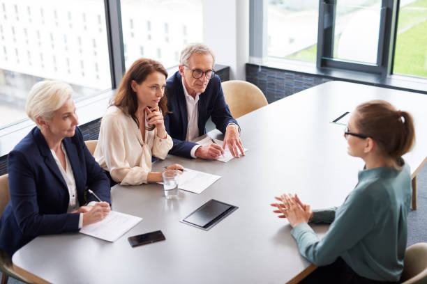 vrouw tijdens sollicitatiegesprek en drie elegante leden van het management - interview stockfoto's en -beelden