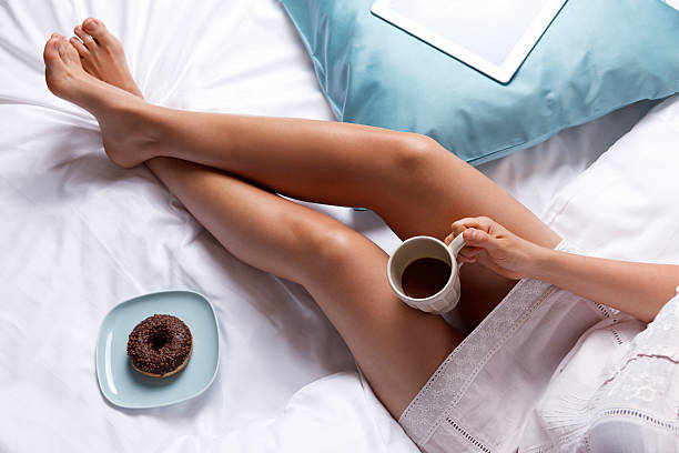 Woman eating a donut in the bed stock photo