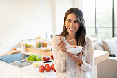 Portrait of a casual woman at home eating a healthy breakfast and looking happy - lifestyle concepts