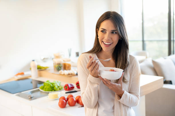 Woman eating a healthy breakfast Portrait of a casual woman at home eating a healthy breakfast and looking happy - lifestyle concepts columbian woman stock pictures, royalty-free photos & images