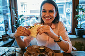 Woman eating a tortilla sandwich at a restaurant.