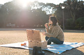 ピクニックでベーグルを食べる女性