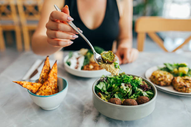 vrouw die falafel in een restaurant eet - veganist stockfoto's en -beelden