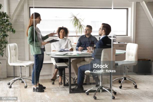 Woman employee talk at team meeting with colleagues in office