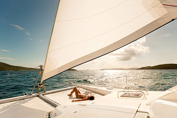 woman enjoying sailing through the Caribbean on a catamaran woman in bikini sunbathing on a catamaran and enjoying sailing through the Caribbean catamaran stock pictures, royalty-free photos & images