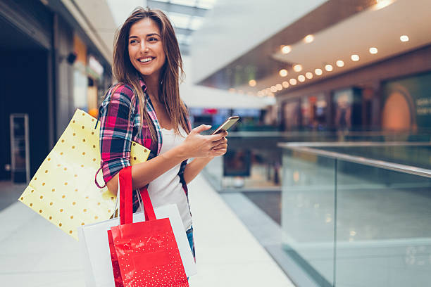 Woman enjoying the day in the shopping mall Happy girl with shopping bags texting on smartphone buying stock pictures, royalty-free photos & images