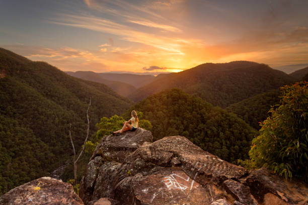Woman enjoying the views overlooking the Grose River and mountains A female relaxes on a rock with stunning wilderness valley views westwards towards the beautiful sunset.  Blue Mountains Australia bush land photos stock pictures, royalty-free photos & images