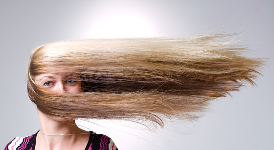 Woman facing straight ahead with hair being blown aside