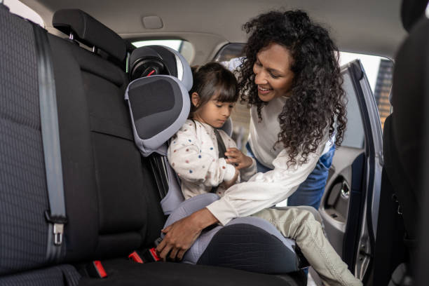 Woman fastening her daughter's seat belt stock photo