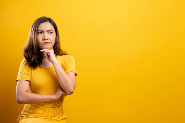 Woman feel confused isolated over yellow background stock photo