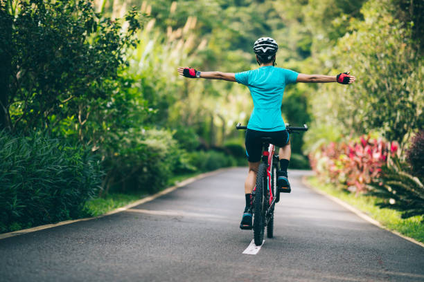 Woman feel free cycling on tropical park trail in summer stock photo
