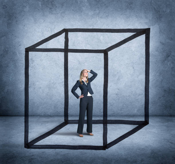 Woman Feeling Boxed In By Cube Drawn Around Her A businesswoman places her hand on her head as she looks up with a sense of concern and confusion as she is trapped within the confines of a cube that has been drawn around her. restraining stock pictures, royalty-free photos & images