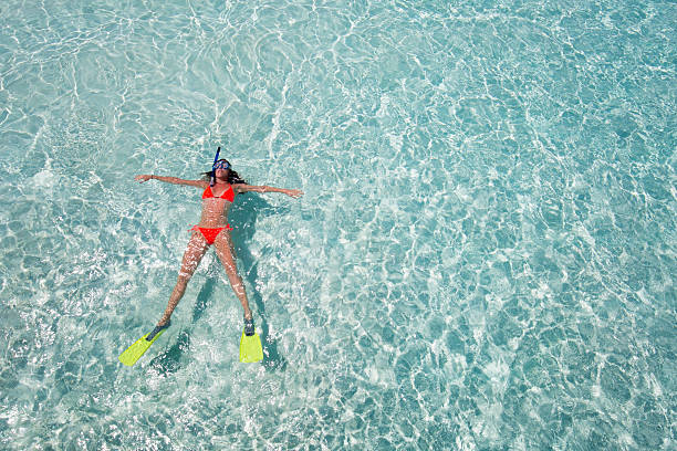 Woman floating on crystal clear waters Woman floating on crystal clear waters with snorkeling gear woman snorkeling stock pictures, royalty-free photos & images