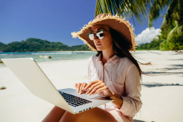 Woman freelancer on the beach Woman freelancer on the beach. Working remotely on the laptop computer through the internet. Working while travelling. Summer vacation in Seychelles. nomadic people stock pictures, royalty-free photos & images