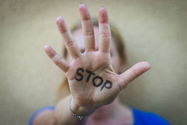 la donna si ferma. messa a fuoco selettiva sulla mano delle femmine aperte con segno di stop scritto. - contro violenza donne foto e immagini stock