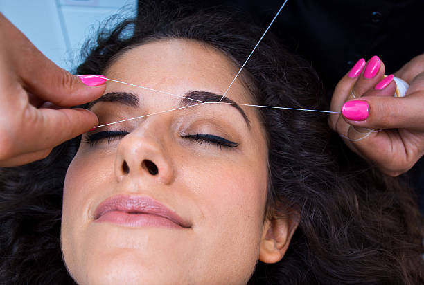 A woman getting her eyebrows threaded stock photo