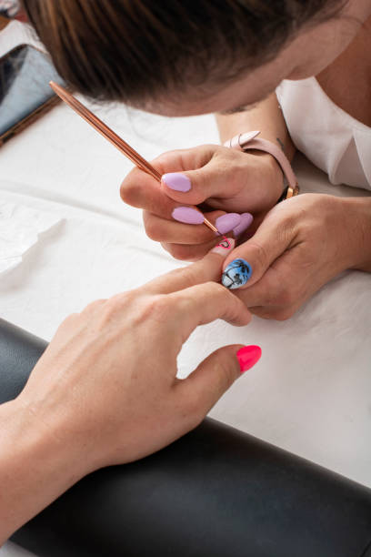 Woman getting her nails done in salon by manicure worker stock photo
