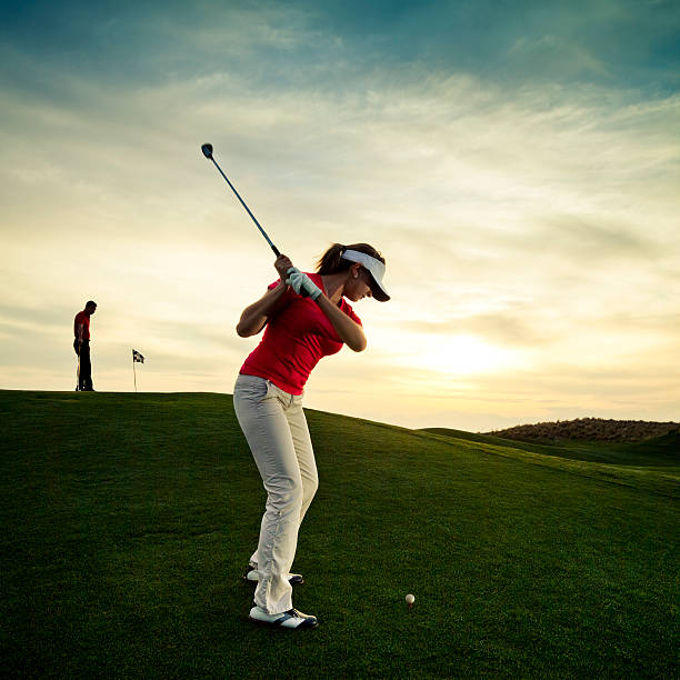 Woman golfer swinging at sunset stock photo