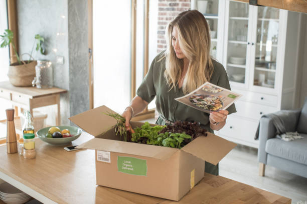 Woman got package from meal delivery service. Woman is received box loaded with organic vegetables from delivery service. She is up to make some fantastic vegan meal home delivery stock pictures, royalty-free photos & images