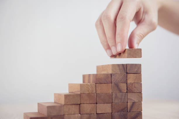 Woman hand arranging wood block stacking as step stair. Business concept growth success process. Close up Woman hand arranging wood block stacking as step stair. Business concept growth success process. bringing home the bacon stock pictures, royalty-free photos & images