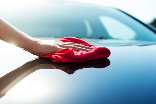 mujer limpiando a mano el coche con toalla roja - microfiber fotografías e imágenes de stock
