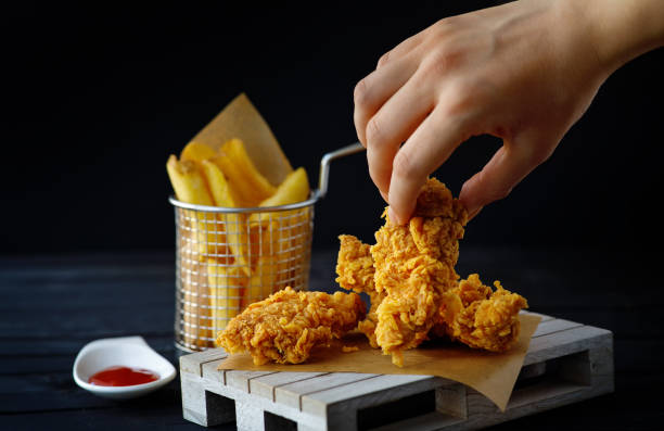 Woman hand holding a crispy chicken strips. Junk food concept. stock photo