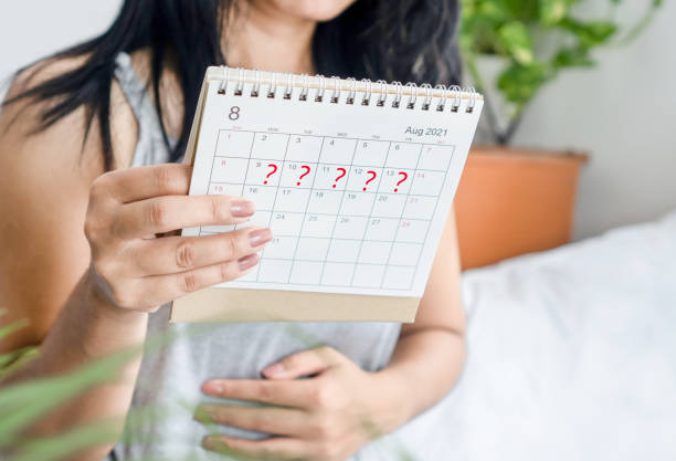 woman hand holding calendar with question mark waiting for late blood period, amenorrhea concept - menstruatie stockfoto's en -beelden
