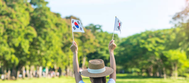 Woman hand holding Korea flag on nature background. National Foundation, Gaecheonjeol, public Nation holiday, National Liberation Day of Korea and happy celebration concepts stock photo