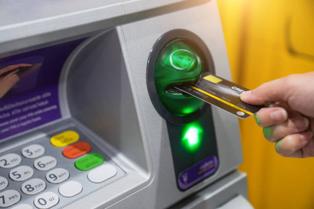Woman hand is inserting card to atm machine to withdraw or transfer money stock photo