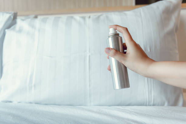Woman Hand is Spraying Air Freshener into Pillow on Bedroom, Unpleasant Smell and Aromatherapy Concept stock photo