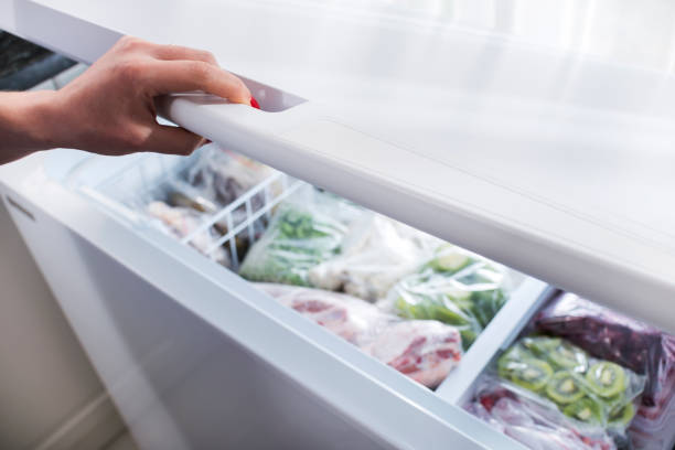 Woman hand opening a refrigerator door stock photo