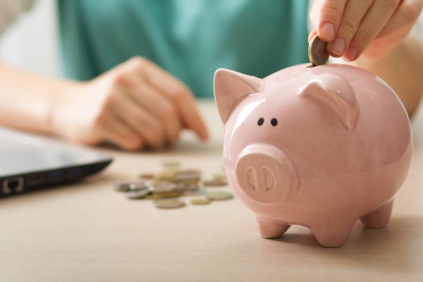 woman hand putting money coin into piggy for saving money wealth and financial concept. stock photo
